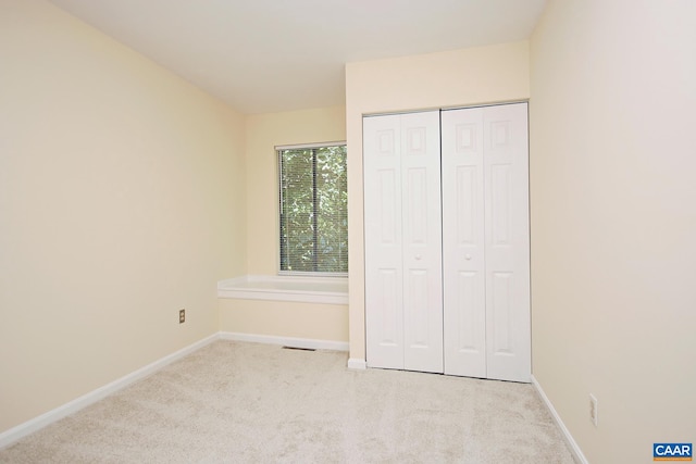 unfurnished bedroom with a closet, visible vents, baseboards, and carpet