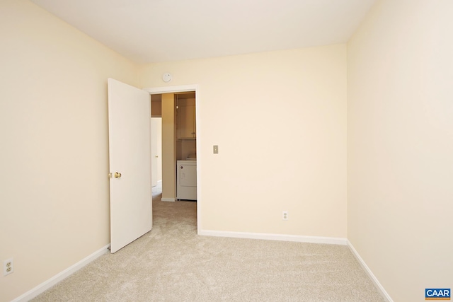 unfurnished room with washer / clothes dryer, baseboards, and light carpet