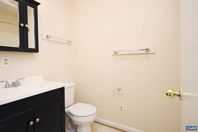 bathroom with toilet, vanity, and baseboards