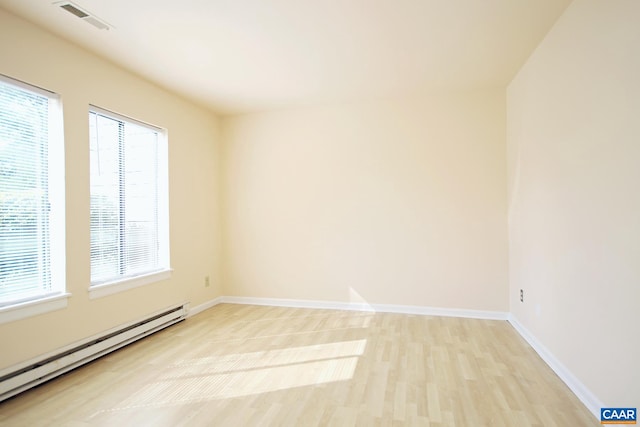 unfurnished room with visible vents, baseboards, baseboard heating, and light wood-type flooring