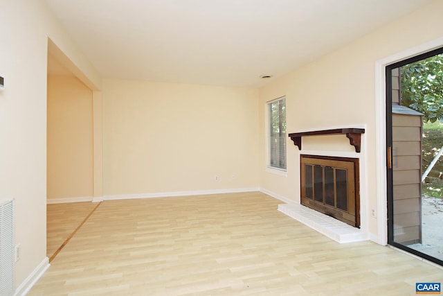 unfurnished living room featuring a fireplace, baseboards, and light wood finished floors