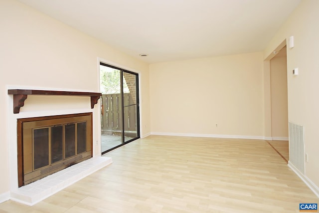 unfurnished living room featuring visible vents, baseboards, a brick fireplace, and wood finished floors