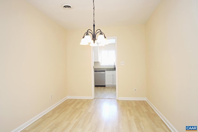 unfurnished dining area featuring an inviting chandelier, visible vents, baseboards, and light wood finished floors