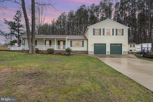 tri-level home featuring a lawn, a garage, concrete driveway, and a porch