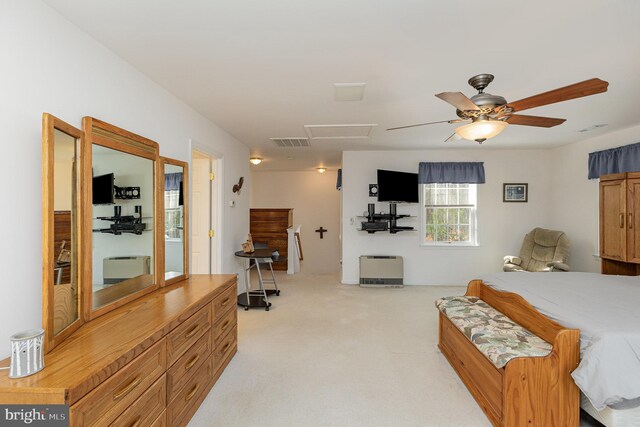 bedroom with a ceiling fan, visible vents, attic access, and light carpet