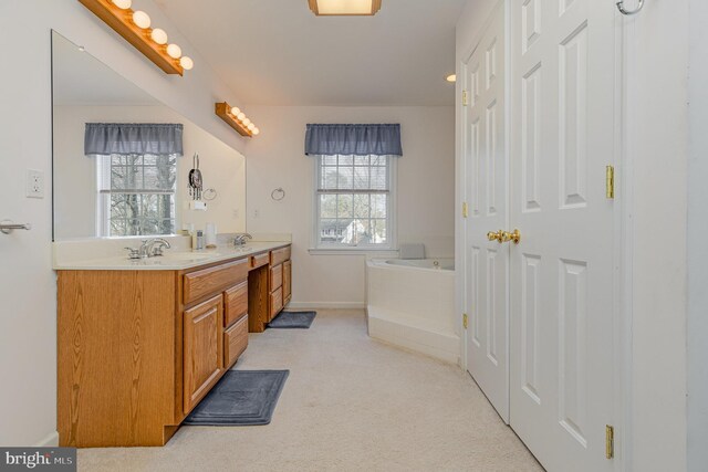 bathroom featuring double vanity, baseboards, a sink, and a garden tub