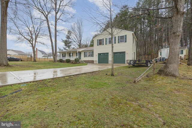 view of front of house with driveway, covered porch, fence, a front lawn, and a garage