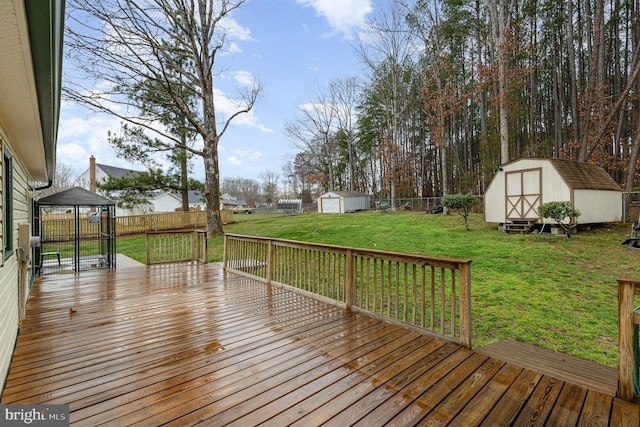 wooden terrace with a fenced backyard, an outbuilding, a storage unit, and a gazebo