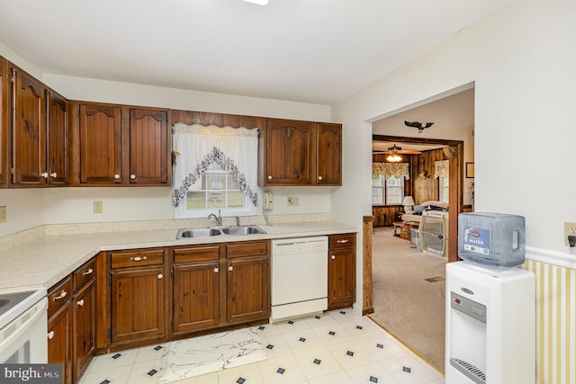 kitchen with light countertops, a sink, light colored carpet, and white appliances