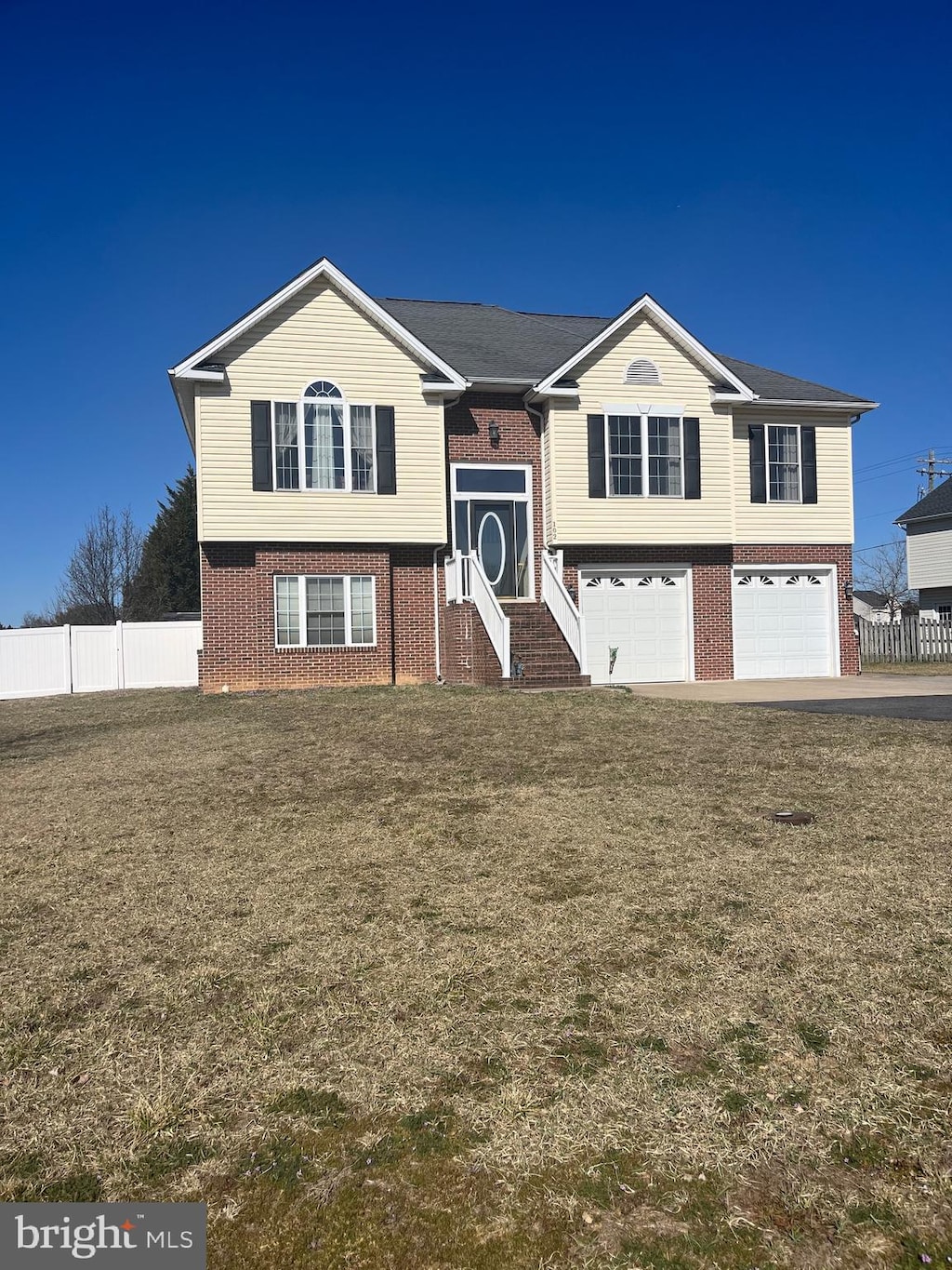 split foyer home with a garage, brick siding, and fence