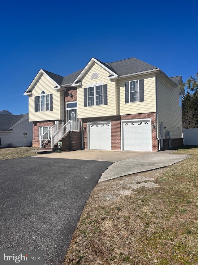 split foyer home featuring brick siding, driveway, and an attached garage