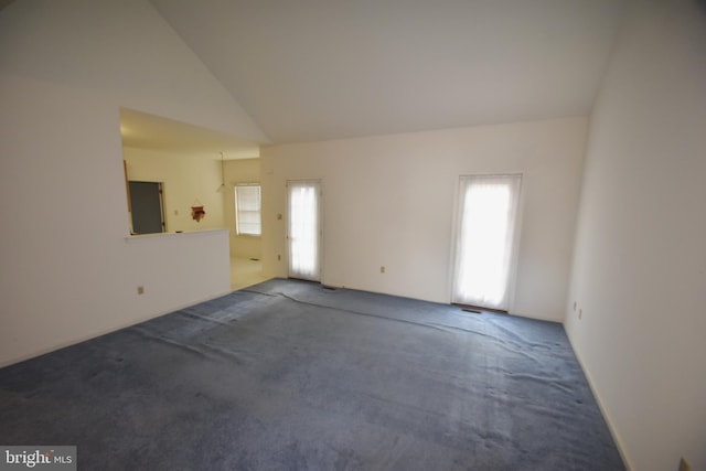 carpeted empty room with high vaulted ceiling