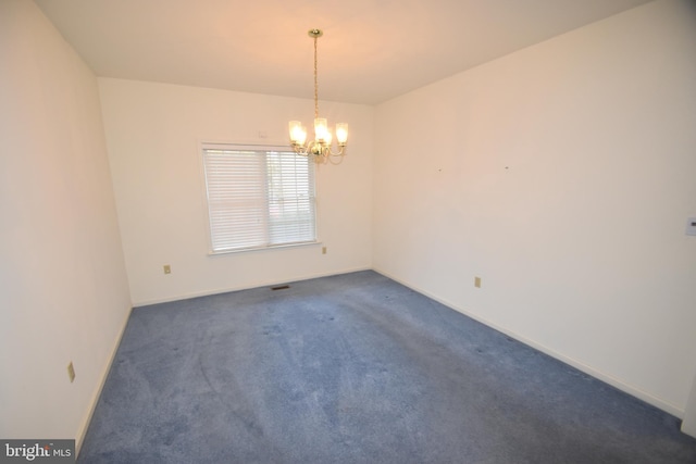 empty room with baseboards, dark carpet, and a chandelier