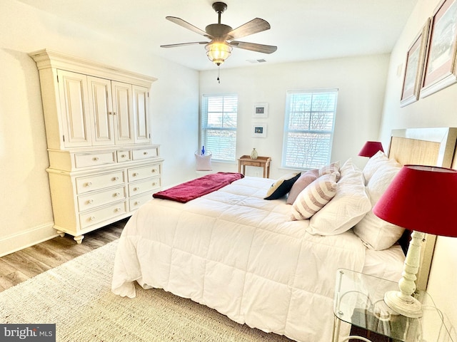 bedroom with visible vents, baseboards, wood finished floors, and a ceiling fan