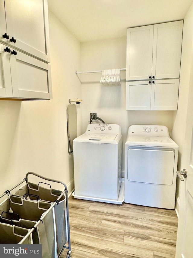 clothes washing area with light wood finished floors, baseboards, cabinet space, and washing machine and clothes dryer