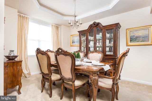 dining space featuring a tray ceiling, light carpet, baseboards, and ornamental molding