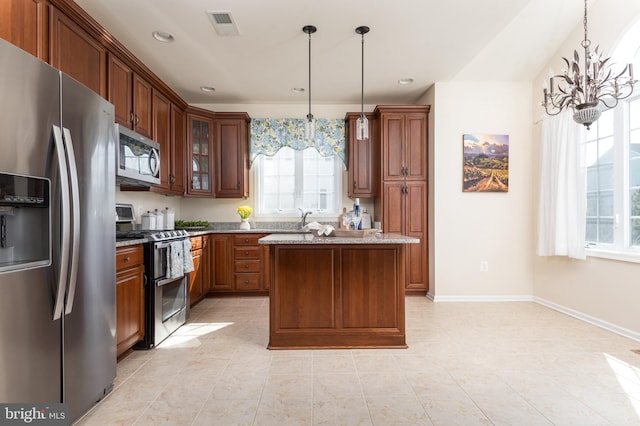 kitchen featuring visible vents, stainless steel appliances, light stone countertops, a chandelier, and hanging light fixtures