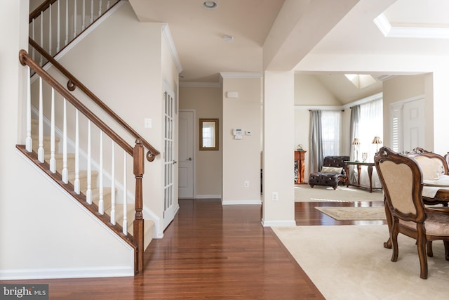 foyer featuring stairs, crown molding, wood finished floors, and baseboards