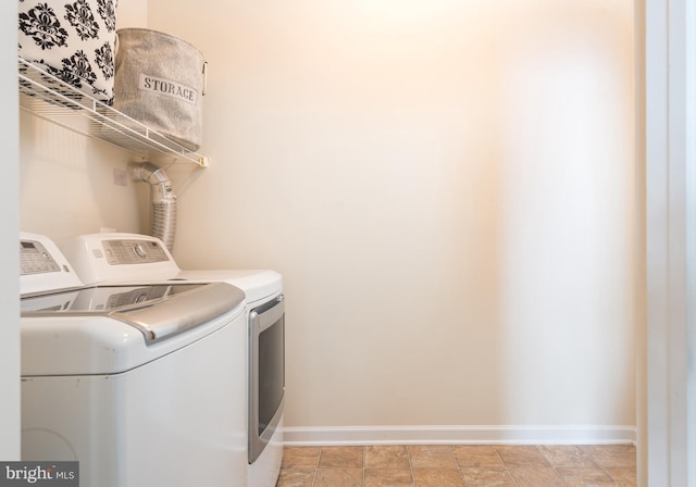 washroom featuring baseboards, separate washer and dryer, and laundry area