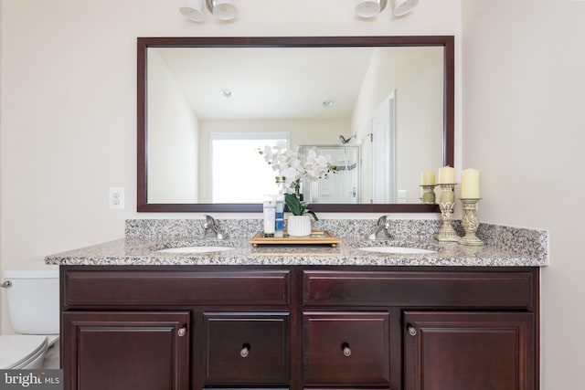 bathroom with double vanity, toilet, walk in shower, and a sink