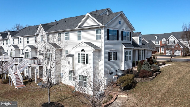 view of home's exterior featuring central air condition unit, stairway, a lawn, and a residential view