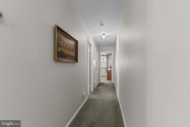 hall with baseboards and dark carpet