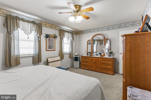 bedroom featuring light carpet, multiple windows, and ceiling fan