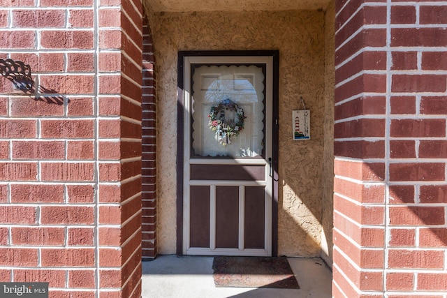 doorway to property featuring brick siding