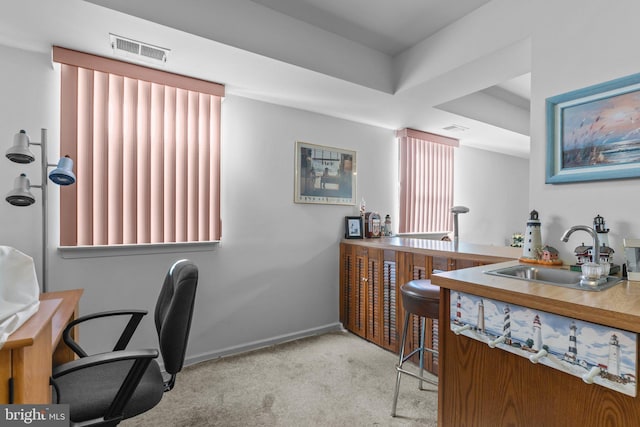 carpeted office with visible vents, a raised ceiling, a sink, baseboards, and wet bar