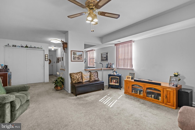 carpeted living room featuring a wood stove, a ceiling fan, and baseboards