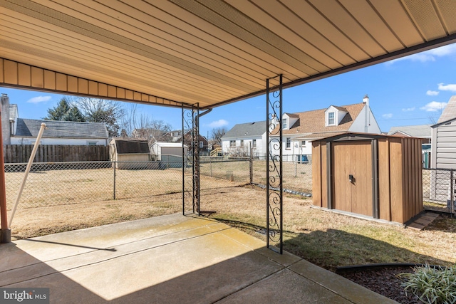 view of patio / terrace with a residential view, fence, an outdoor structure, and a shed