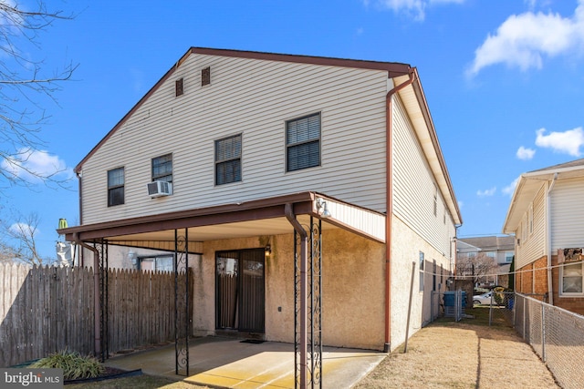 view of front of property with a patio area, cooling unit, fence, and stucco siding