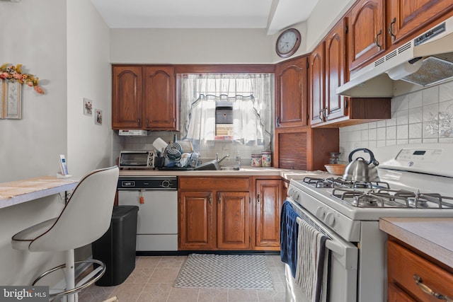 kitchen featuring white appliances, a sink, decorative backsplash, light countertops, and under cabinet range hood