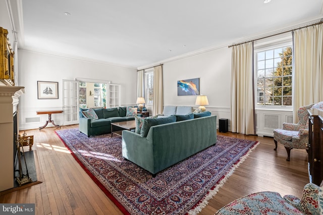 living room featuring visible vents, a fireplace, french doors, wood-type flooring, and crown molding