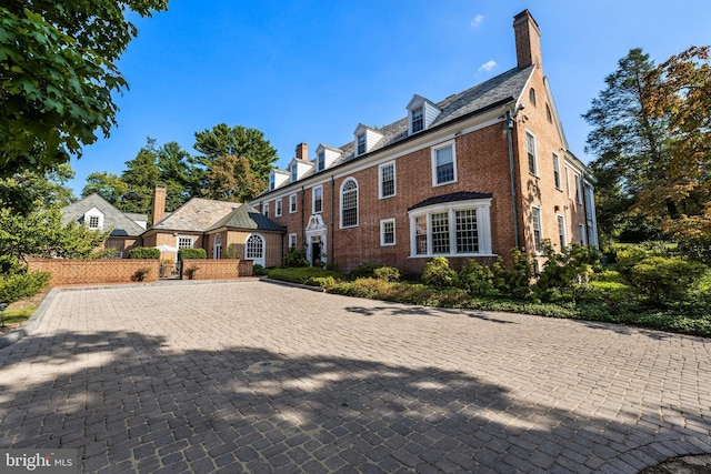 exterior space with a high end roof, brick siding, and a chimney