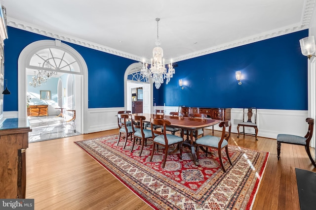 dining room with an inviting chandelier, wood finished floors, and a wainscoted wall