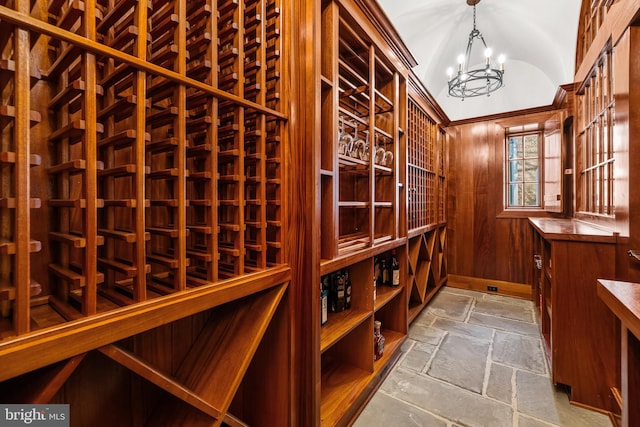 wine room with a notable chandelier, stone tile floors, and wooden walls