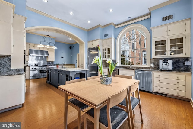 dining space with light wood-type flooring, visible vents, and ornamental molding