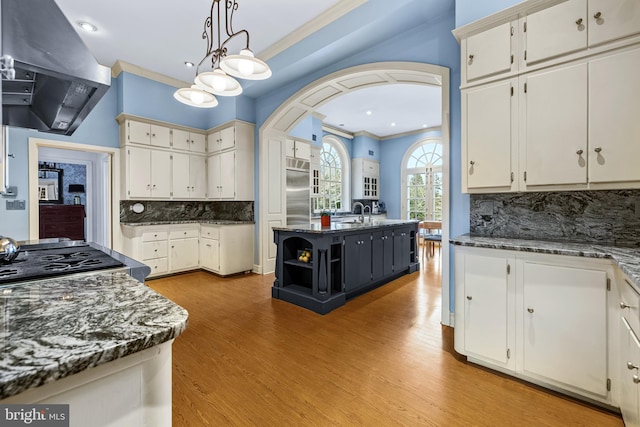 kitchen with stainless steel built in fridge, exhaust hood, crown molding, and white cabinetry