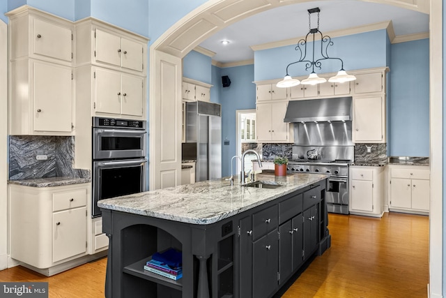 kitchen featuring arched walkways, a sink, under cabinet range hood, crown molding, and high quality appliances