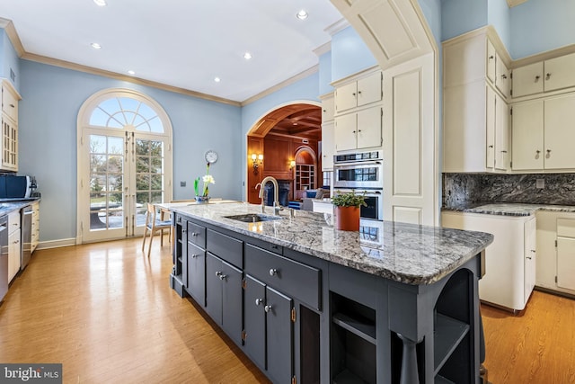 kitchen with tasteful backsplash, a sink, light wood-style floors, stainless steel appliances, and open shelves