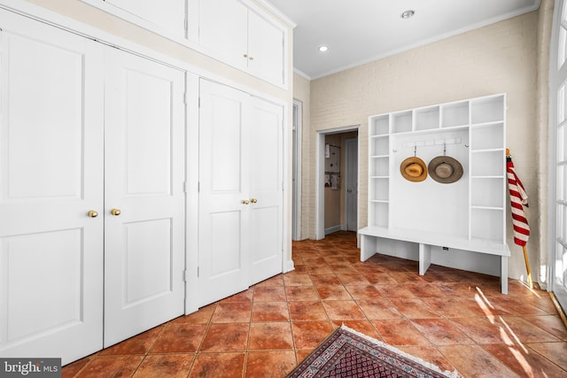 mudroom featuring brick wall, tile patterned flooring, and ornamental molding