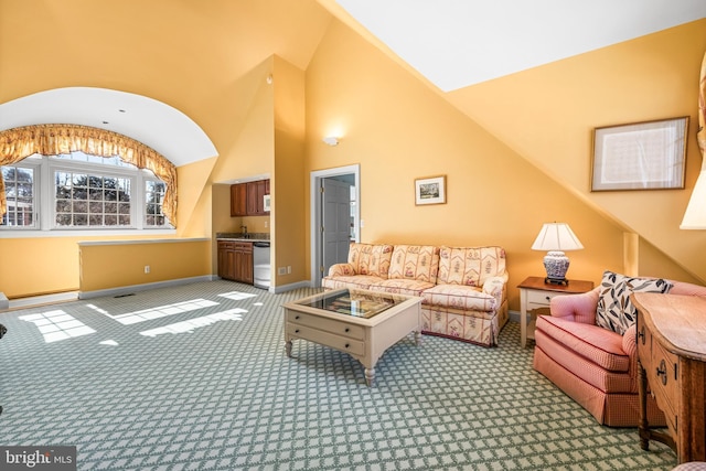 carpeted living area featuring baseboards and high vaulted ceiling