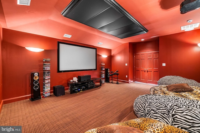 carpeted home theater room with vaulted ceiling, baseboards, and visible vents