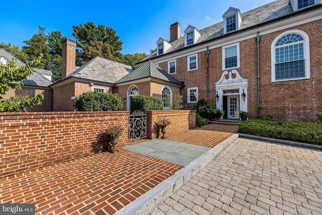 view of front of house featuring brick siding, a high end roof, and a gate