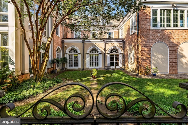 view of front of property featuring french doors, brick siding, and a front yard