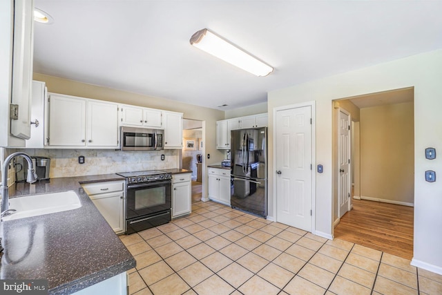 kitchen featuring black appliances, a sink, dark countertops, light tile patterned floors, and decorative backsplash