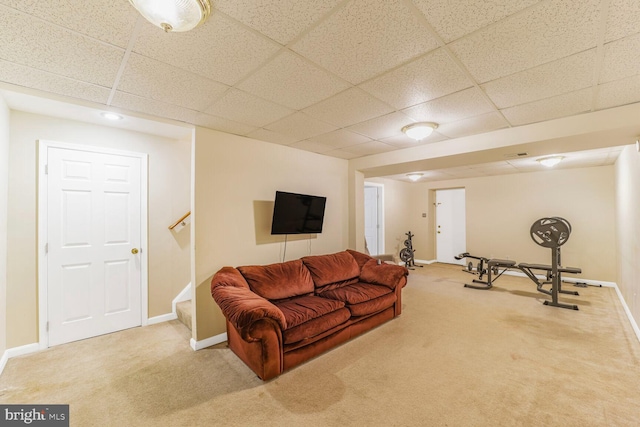 carpeted living room featuring a paneled ceiling, baseboards, and stairs