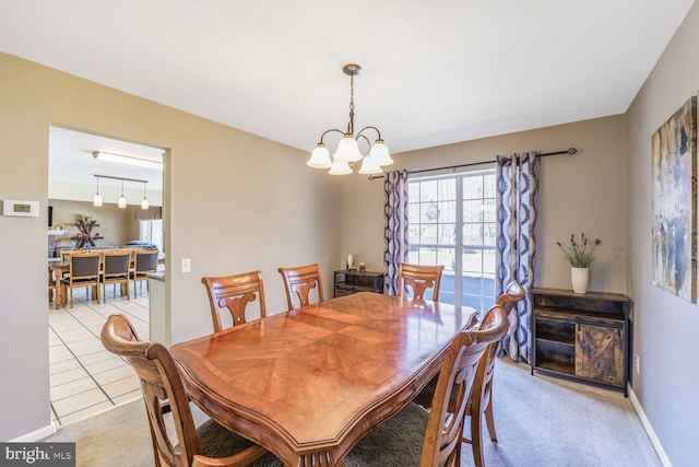 dining space featuring light tile patterned flooring, a notable chandelier, light colored carpet, and baseboards