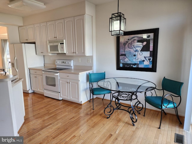 kitchen featuring white appliances, white cabinets, visible vents, and light wood-type flooring